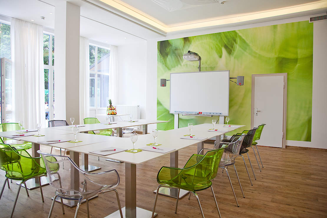 Tagungsraum mit grünen Stühlen und einer grünen Wand